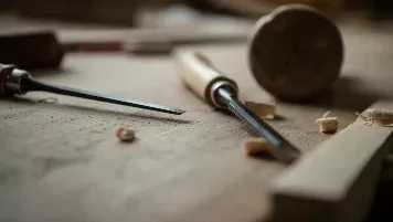 ciseau à bois et maillet en bois posé sur une pièce de bois