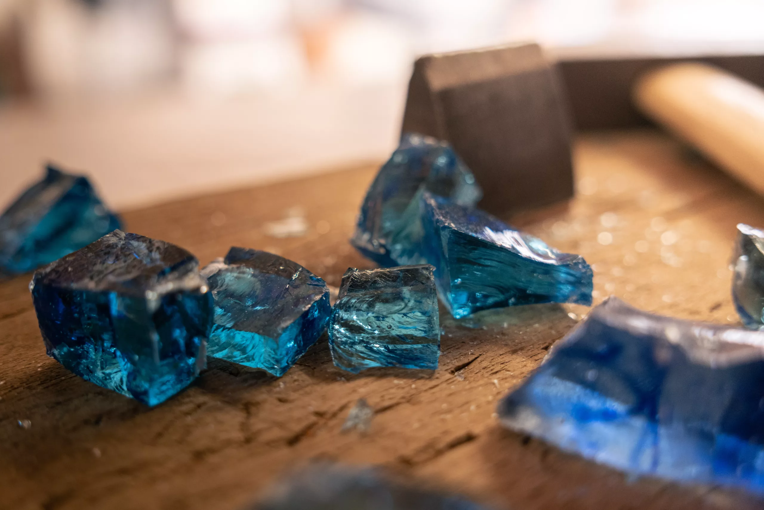 tesselles bleues roi, en verre translucide en cours de coupe sur un plan de travail, avec un marteau