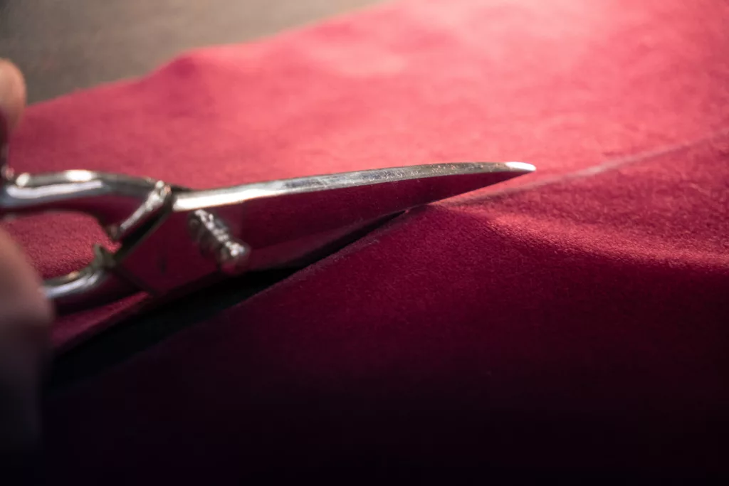 découpe de tissu rouge avec une paire de ciseaux de couture