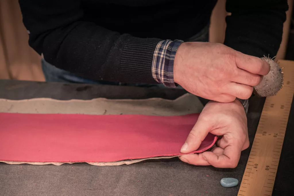 fabrication d'ouvrage en cours, tissu rouge sur un plan de travail et utilisation d'épingles