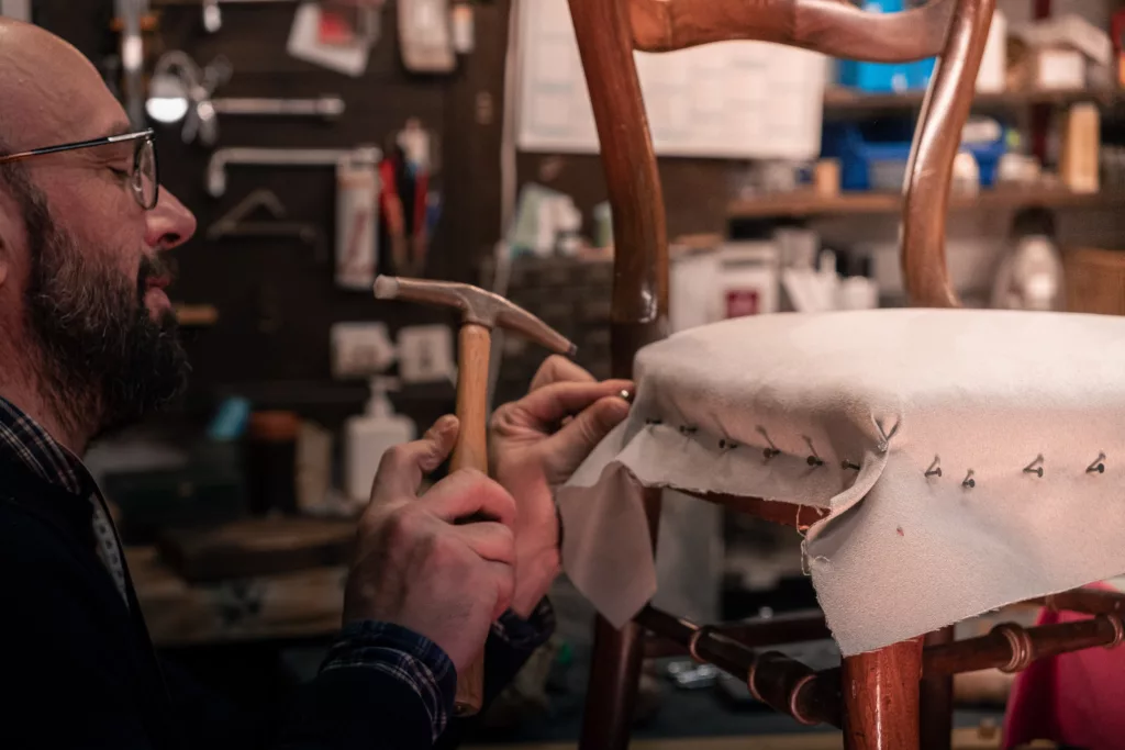 travail en cours sur un siège, mise en place de la toile blanche fixée par des semences à l'aide du ramponeau
