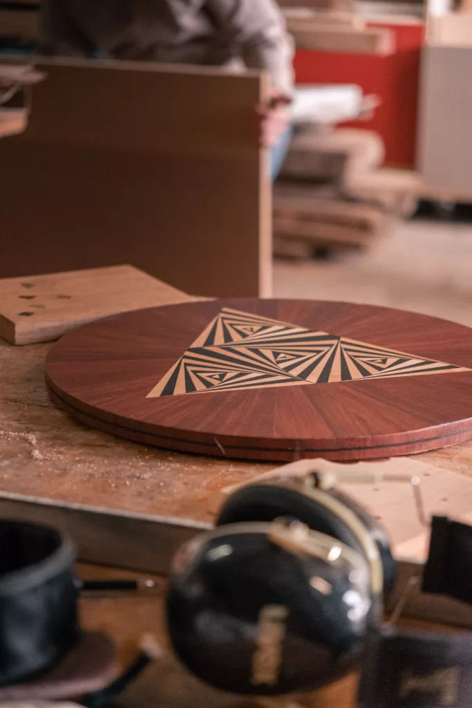 pièce de bois foncé ronde avec un triangle au centre marqueté en bois clair et brun