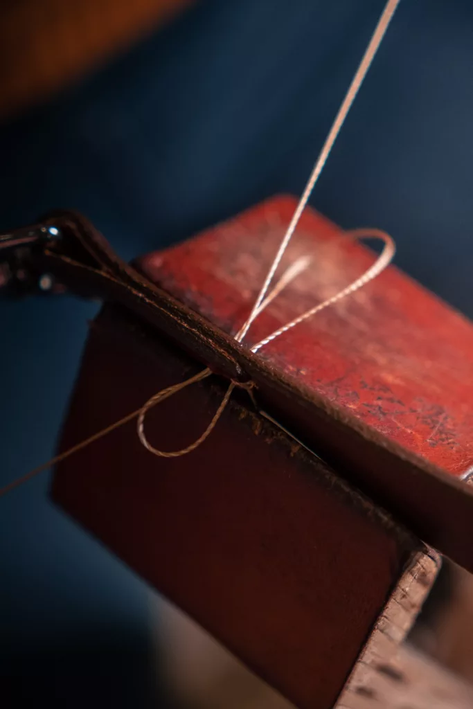 travail de la couture sellier à la main sur une pièce de cuir marron