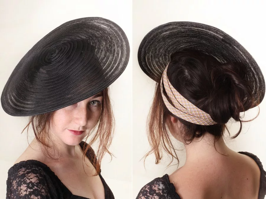 un chapeau noir avec un bandeau rose pâle est dressé sur la tête d'une femme